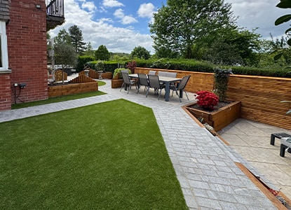 Full garden landscaping with artificial grass, paving, and planting beds